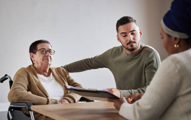 Young male caregiver listening on how to provide support for his elder mom who is in a wheelchair