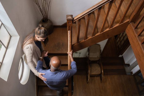 Home caregiver helping senior man walking up the stairs at home