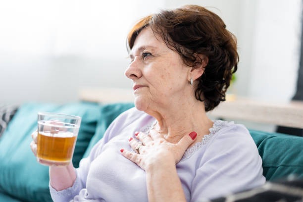 senior woman drinking a warm drink to manage pain from gas