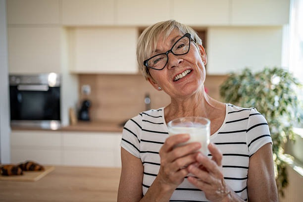  Senior woman holding a glass of milk, while enjoying a nutritious breakfast