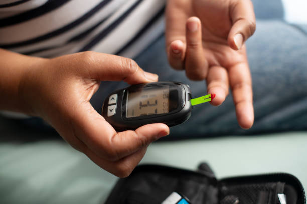 Glucometer, lancet and hands in closeup for blood, test and reading for numbers, wellness and sugar level. Machine, needle and person with diabetes with screen to monitor glucose in home for health